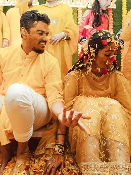The couple, covered in Haldi, share a quiet, happy moment together amidst the celebration.