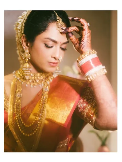 A stunning portrait of a South Indian bride, highlighting the intricate details of her jewelry and the traditional red and white bangles (chooda).