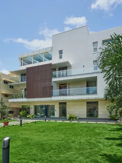 Another view of the 'Wilasa' villa, where the minimalist facade with its clean lines and material contrast is complemented by the lush green lawn. The design creates a harmonious balance between modern architecture and nature.
