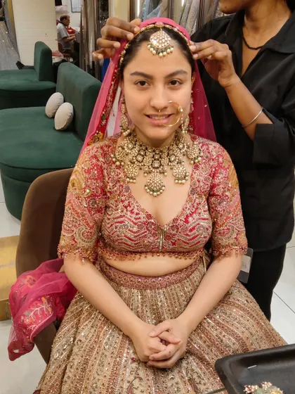 A happy bride during her jewellery trial at our store. She is wearing a heavy, traditional Polki bridal set with a matching maang tikka and nath, looking absolutely radiant.
