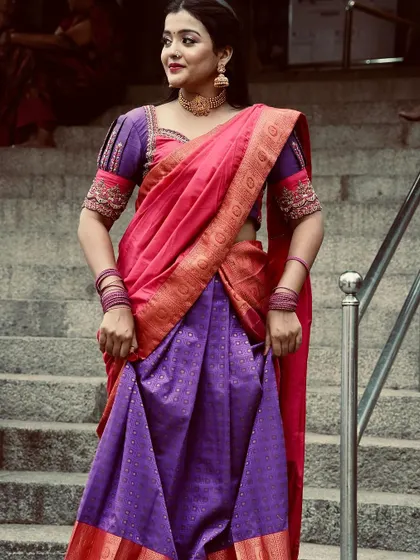 Adjusting the skirt of the half saree, this shot shows the rich fabric and traditional design of the outfit.