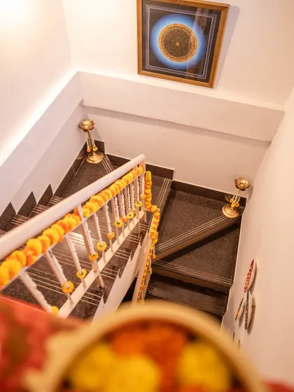 A view down a staircase with the railing decorated in marigold garlands, showing how we carry the festive decor throughout the entire event space.