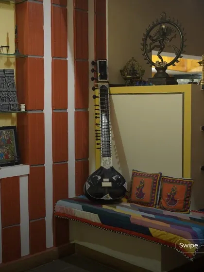 A corner dedicated to art and music, featuring a sitar, traditional Indian brass lamps (diyas), and other artifacts. This space is a personal gallery that reflects the cultural identity of the homeowners.