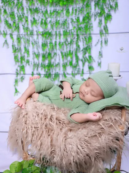 A slightly different angle of the botanical-themed newborn shoot. The focus is on the baby's peaceful pose and the soft textures of the props.