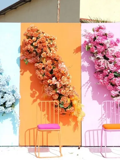 A fun and colorful photo wall for a carnival-themed event. The wall features panels in pastel shades with matching chairs and cascading flowers.