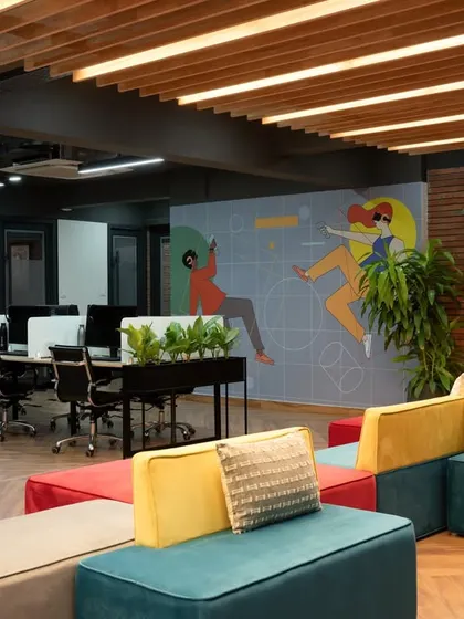 A wide view of the main huddle space, featuring the iconic red phone booth, colorful seating, and a large wall mural. This area is the social and collaborative heart of the office.