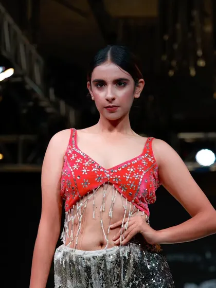 This look features a detailed, embellished top with a sparkling skirt. I ensure the runway pace allows the audience and cameras to appreciate the craftsmanship of each piece.