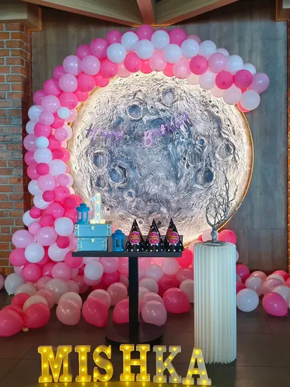 A wide-angle shot of the unique moon-themed first birthday setup for Mishka, showing the full scale of the balloon arch and stage decor.