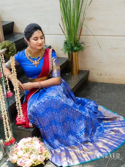 A beautiful Telugu look for a bangle ceremony. The makeup is kept fresh and traditional to complement the vibrant blue and red half-saree and classic gold jewellery.