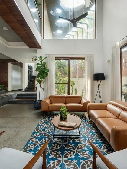 Another view of the living area, highlighting the interplay of textures. The cool concrete floor is balanced by the warmth of the leather sofa and the vibrant pattern of the Athangudi tiles, adding a touch of vernacular craft to the modern space.