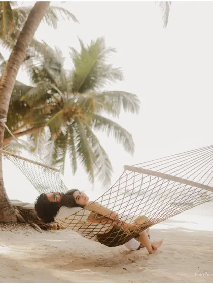 A serene shot of the couple relaxing in a hammock under the shade of a palm tree, creating a peaceful and romantic image.