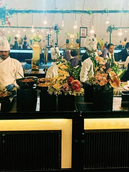 A full view of a large-scale buffet line, showcasing the coordinated look with my chefs in uniform. The sleek black counters with warm under-lighting create a professional and sophisticated atmosphere.
