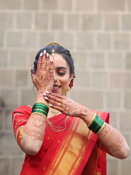 A creative pose showing off the detailed henna art. The makeup is kept soft and radiant, with a focus on flawless skin and expressive eyes.