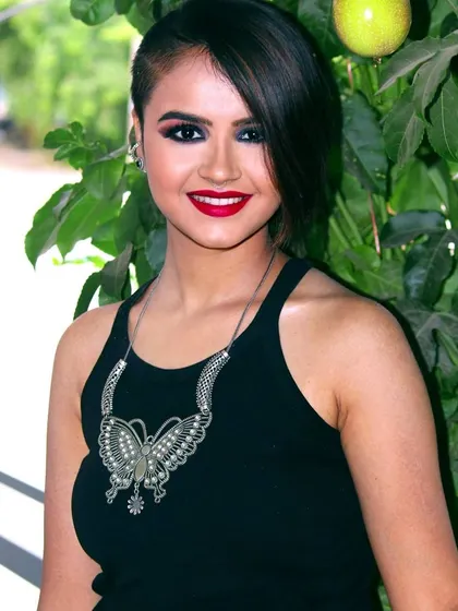 A smiling shot that shows how a bold makeup look can still feel bright and approachable. The dark smokey eye and red lip are paired with a confident smile, perfect for any social event.