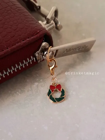 The Christmas wreath charm attached to a wallet, adding a simple and elegant festive touch.