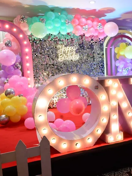 A silver shimmer wall provides a bright and festive background for these "ONE" marquee letters at a first birthday party.
