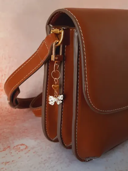 The same white and gold bow charm, shown from a different angle to highlight its delicate details.
