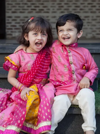 The infectious laughter between siblings is priceless. This shot captures a moment of shared joy between a brother and sister in their festive clothes.