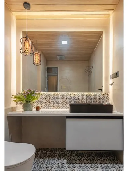 We created a rustic-modern bathroom with patterned floor and wall tiles that evoke a traditional feel. This is contrasted with a modern black vessel sink, a large backlit mirror, and vintage-style pendant lights for a unique blend of styles.