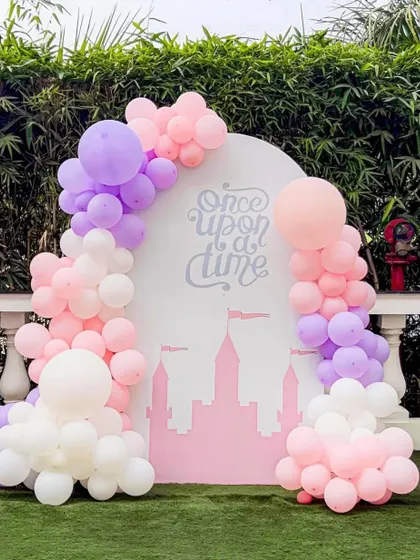 A "Once Upon a Time" backdrop for a princess party. The design features a castle silhouette against a pink background, framed by a dreamy pastel balloon arch.