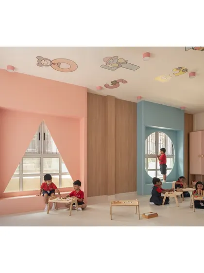 This classroom features unique architectural details like large, shaped window nooks that double as cozy reading spots. The mix of pink and blue tones creates a soft, playful environment for young learners.