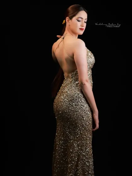 This shot highlights the stunning backless design of the gold sequin gown, adding a touch of allure to its glamorous look.