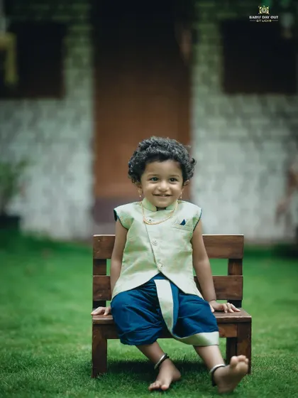 A handsome little boy in a traditional veshti, sitting proudly on a bench in our garden. We love capturing cultural outfits.