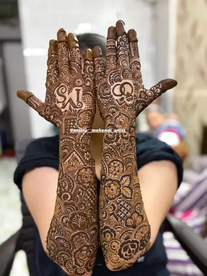 A full view of the 'MS' engagement mehendi, showcasing the symmetrical yet unique designs on both arms, extending all the way to the elbows.