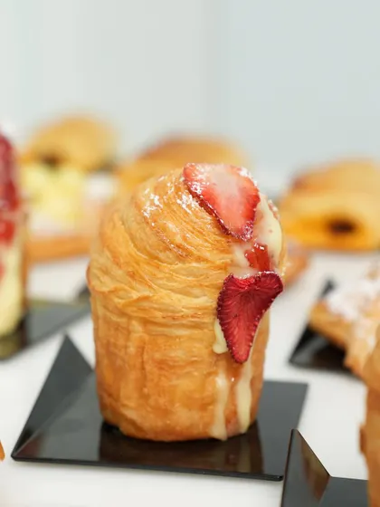 A close-up of a strawberry cruffin, showcasing its beautiful laminated texture and delicious filling.