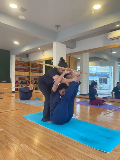 Another angle of our partner stick yoga, showing the trust and communication required to hold the pose.