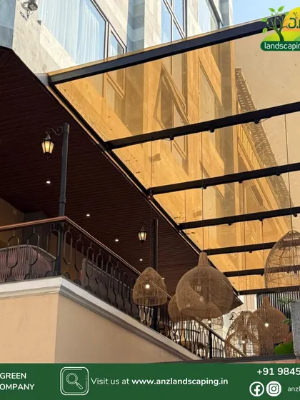 This elegant pergola features a tinted glass roof that provides shade while adding a warm, golden hue to the space below. The design is complemented by stylish wicker pendant lights.