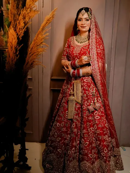 A full-length shot of the bride in her stunning red lehenga, a timeless portrait that captures her grace and beauty on her special day.