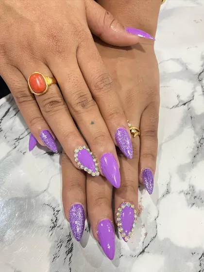 This bold purple set is perfect for making a statement. It combines a glossy purple polish with purple glitter and large heart-shaped rhinestone clusters on the accent nails.