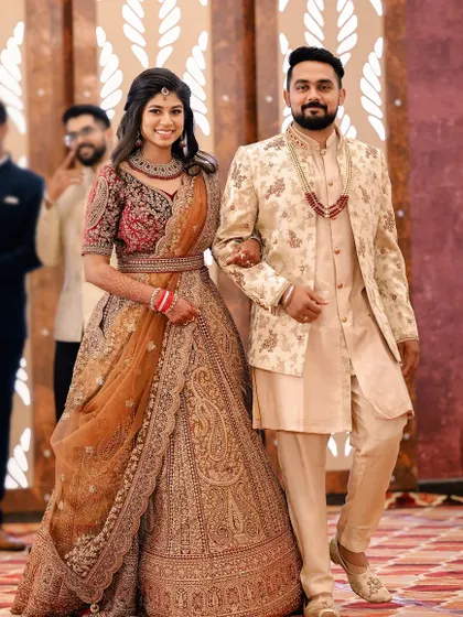 The grand entrance of the couple at their reception. Pooja's makeup is radiant and camera-ready.