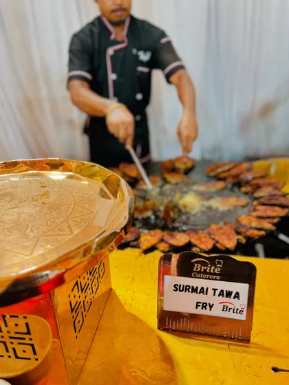 A chef in action, frying Surmai on a large tawa.