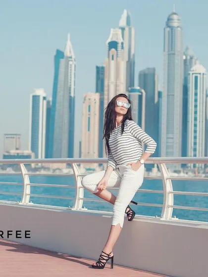 A wider angle of the Dubai Marina shoot, emphasizing the grand scale of the skyscrapers. The model's relaxed pose contrasts with the towering city, creating a cool, effortless vibe.