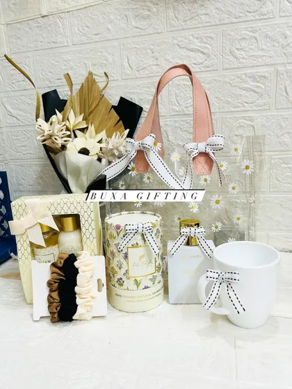 The contents of the all-white hamper displayed before being placed in the bag, showing the perfume, candle, mug, scrunchies, and skincare set.