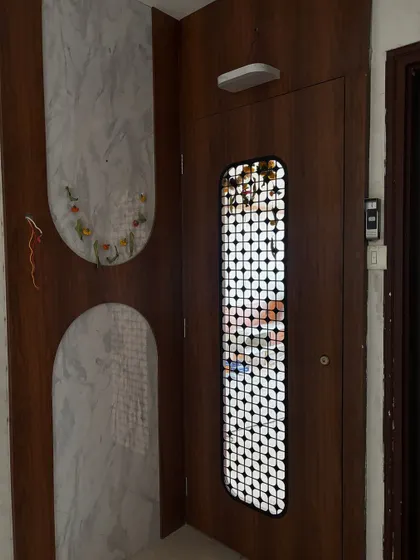 The foyer area next to the door features decorative wall panels with marble and wood finishes, continuing the design theme.