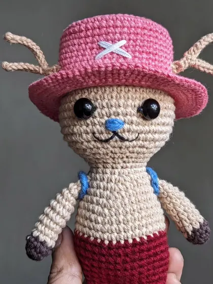 A handmade doll of Tony Tony Chopper from the anime series One Piece. He's wearing his signature pink hat with a white 'X' on it.