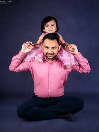 A father's joy is evident as his little daughter sits on his shoulders. This pose is a classic for a reason, showing trust, fun, and the special bond they share.