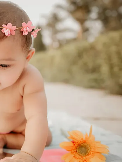 Another detail from the first birthday outdoor shoot. This tightly cropped image focuses on the baby's profile and her intent gaze, capturing a quiet, thoughtful moment amidst the celebration and play.
