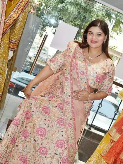 A client trying on a lovely peach and pink floral embroidered lehenga in the store. This is a great option for bridesmaids or as a wedding guest outfit.