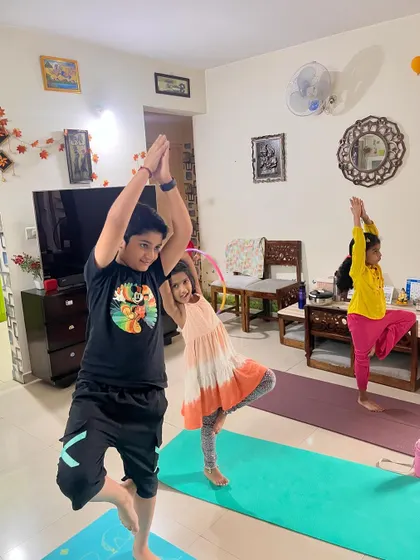 Three young clients practice Tree Pose (Vrikshasana), a classic balance pose that improves focus and stability.