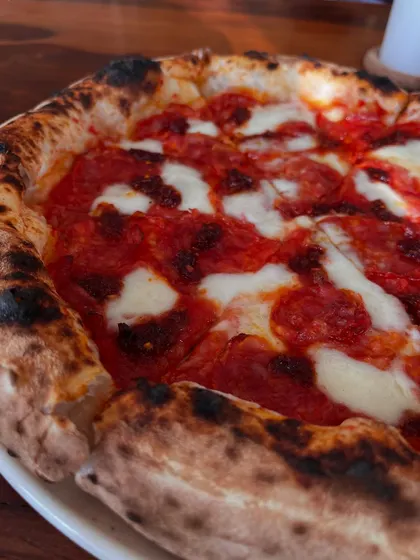 A close-up of the Nduja & Soppressata pizza, with its beautiful charred crust.