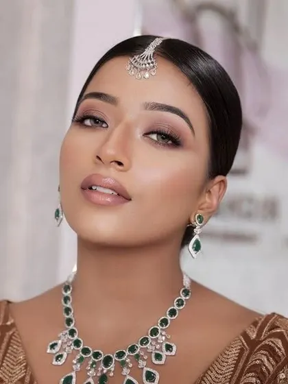 A soft bridal glam look on a beautiful dusky skin tone. The makeup is designed to create a golden goddess glow, proving that soft, radiant makeup looks stunning on every complexion.
