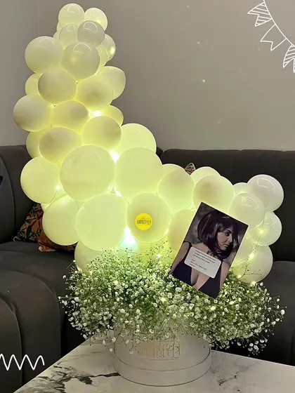 A dreamy, glowing bouquet featuring a moon-shaped arrangement of white balloons with fairy lights, floating above a box of fresh baby's breath.