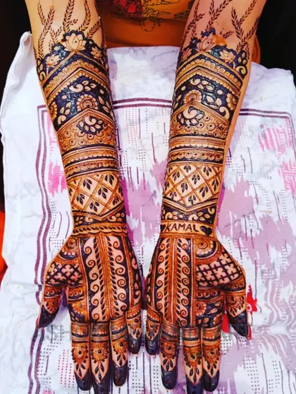 This full-hand bridal design cleverly integrates the name 'Kamal' into the intricate patterns on the wrist. It's a subtle yet beautiful way to personalize the traditional bridal mehndi.