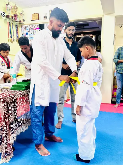 Tying a yellow belt, recognizing the hard work and basic skills this young student has learned.