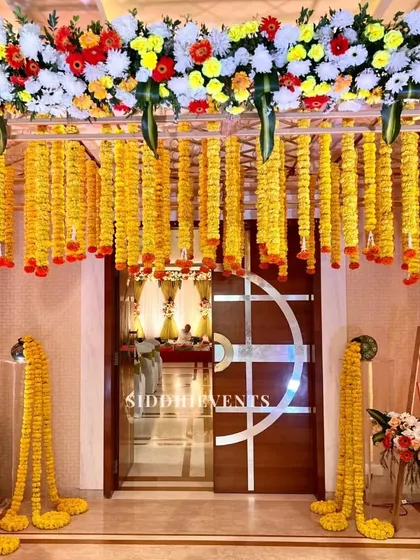 An entrance decorated with radiant yellow marigold garlands hanging from a floral canopy, creating a traditional and cheerful welcome for a wedding event.