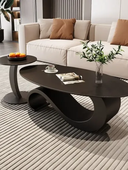 This unique center table features a sculptural, wave-like base in a dark matte finish, paired with a matching circular side table. It's a true statement piece for any living room.